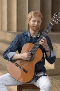 Miles McConnell, guitarist, holding a guitar